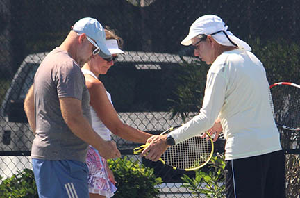 instructor teaching couple learning how to play tennis